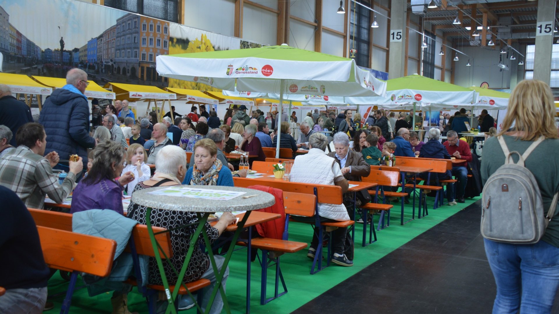Genussland Bereich auf der Messe Ried mit vielen essenden Besucher:innen auf Biertischen..