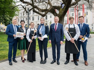 Feierliches Gruppenfoto mit den vier Schüler:innen, dem Landeshauptmann, dem Direktor der Baletour und Margit Steinmetz-Tomala